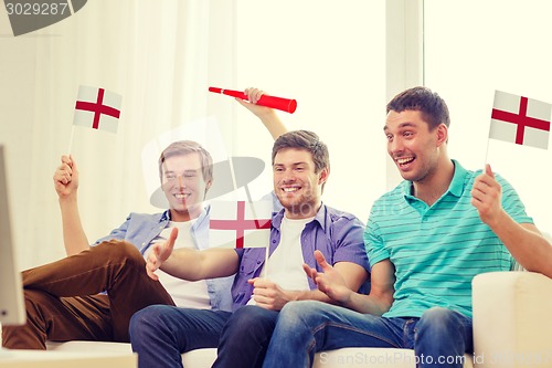 Image of happy male friends with flags and vuvuzela