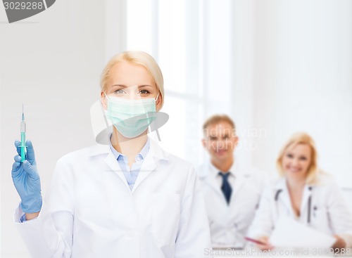 Image of doctor in mask holding syringe with injection