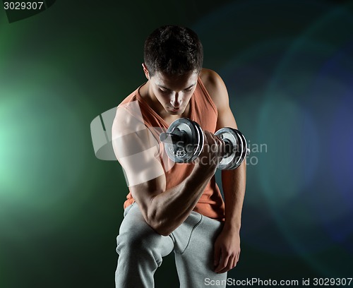 Image of young man with dumbbell flexing biceps