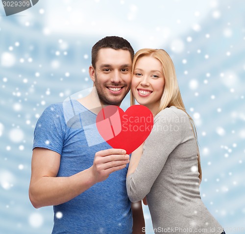 Image of happy couple with red heart shape hugging outdoors