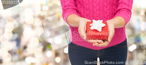 Image of close up of woman in pink sweater holding gift box