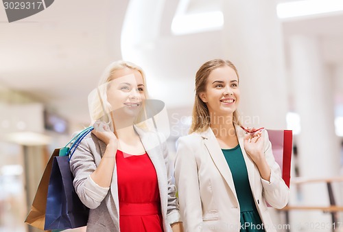 Image of happy young women with shopping bags in mall