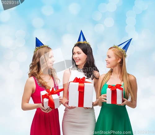 Image of smiling women in party caps with gift boxes