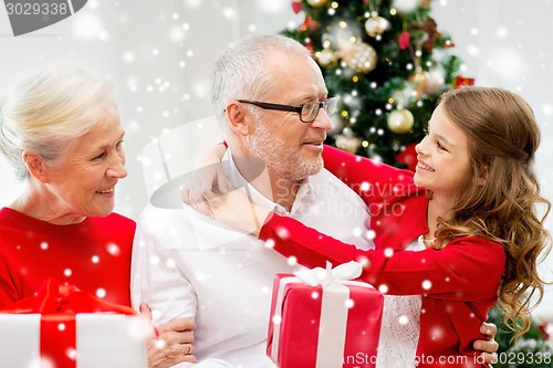 Image of smiling family with gifts at home