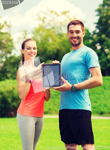 Image of smiling couple with tablet pc outdoors
