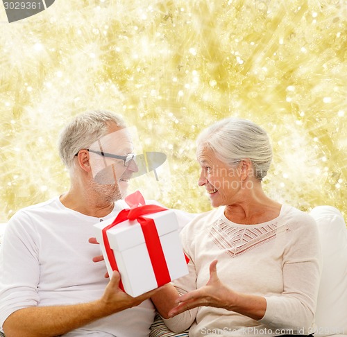 Image of happy senior couple with gift box at home