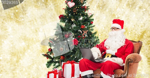 Image of man in costume of santa claus with laptop