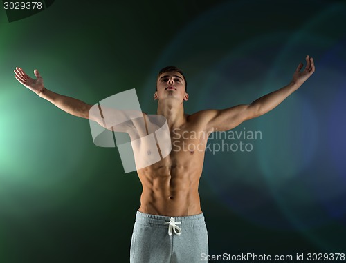 Image of young male bodybuilder with raised hands