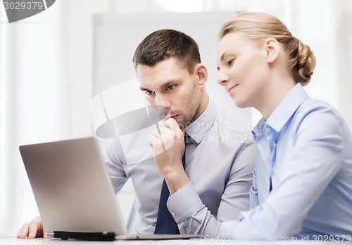 Image of serious business couple with laptop computer