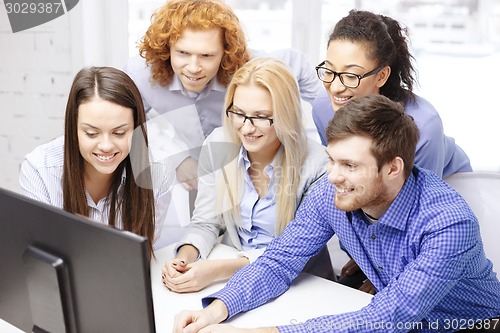 Image of smiling business team looking at computer monitor