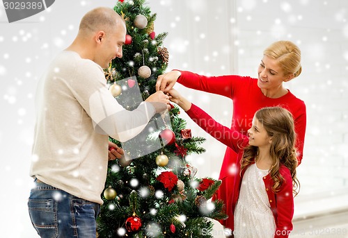 Image of smiling family decorating christmas tree at home