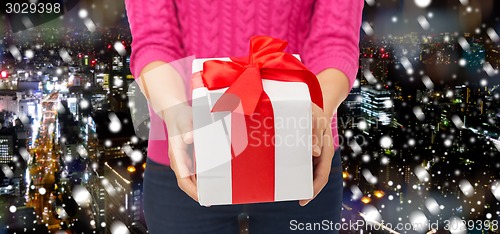 Image of close up of woman in pink sweater holding gift box