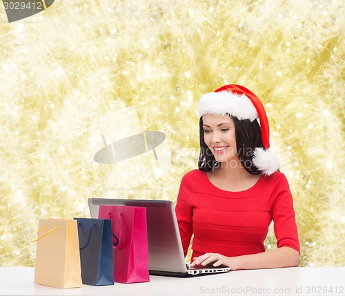 Image of smiling woman in santa hat with bags and laptop