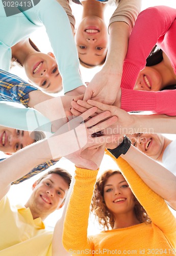 Image of smiling teenagers with hands on top of each other