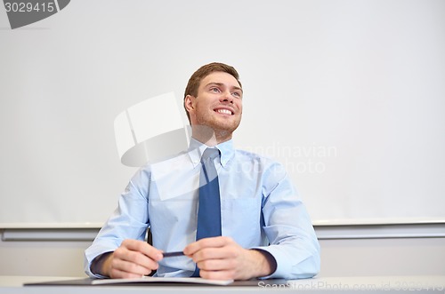 Image of smiling businessman sitting in office