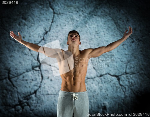 Image of young male bodybuilder with raised hands