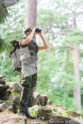 Image of soldier with binocular and backpack in forest