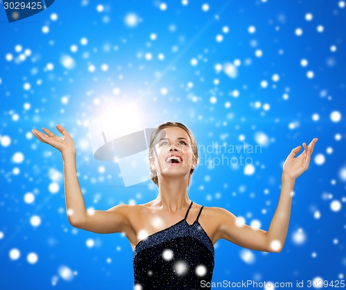 Image of smiling woman raising hands and looking up