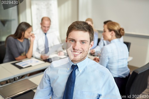 Image of group of smiling businesspeople meeting in office