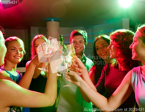 Image of smiling friends with wine glasses and beer in club