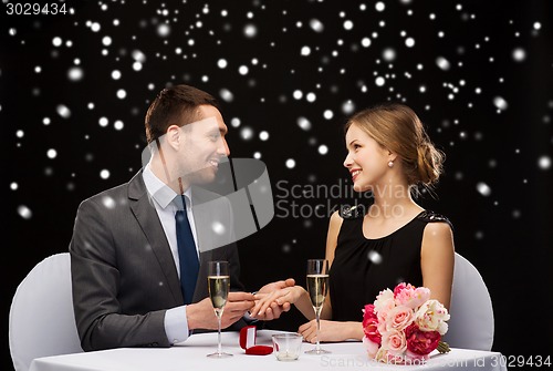 Image of smiling couple with red gift box at restaurant