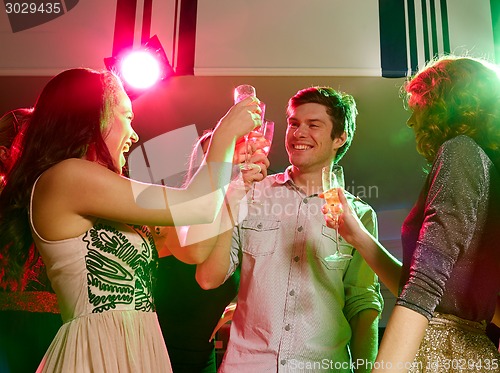 Image of smiling friends with glasses of champagne in club