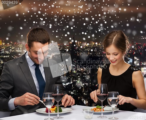 Image of smiling couple eating main course at restaurant