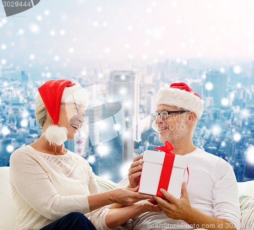 Image of happy senior couple with gift box at home