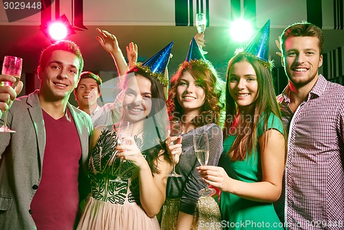 Image of smiling friends with glasses of champagne in club