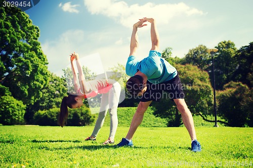 Image of smiling couple stretching outdoors