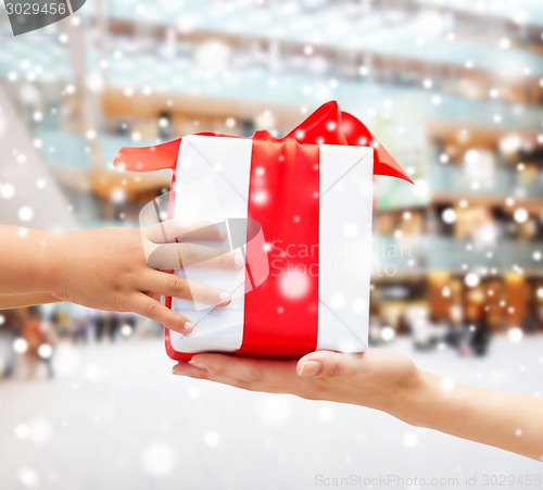 Image of close up of child and mother hands with gift box