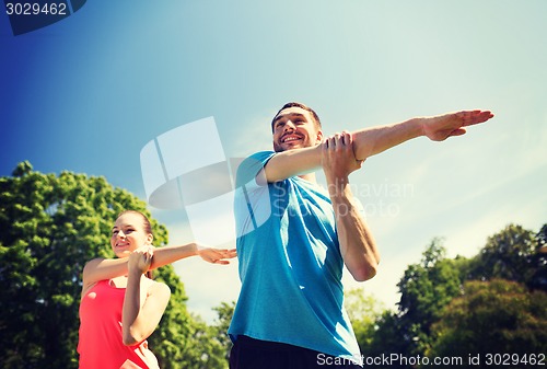 Image of smiling couple stretching outdoors