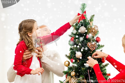 Image of smiling family decorating christmas tree at home