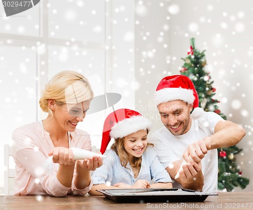 Image of happy family in santa helper hats cooking