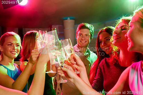 Image of smiling friends with wine glasses and beer in club