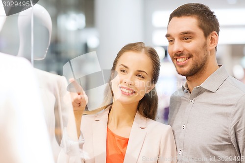 Image of happy couple pointing finger to shop window