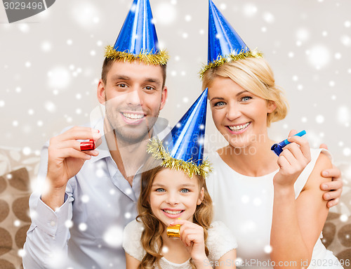 Image of smiling family in party hats blowing favor horns