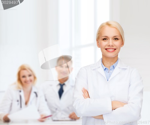 Image of smiling female doctor with group of medics