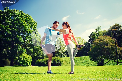 Image of smiling couple stretching outdoors