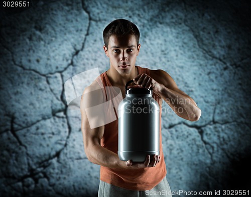 Image of young male bodybuilder holding jar with protein