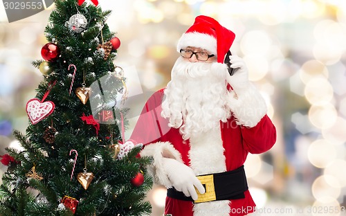 Image of santa claus with smartphone and christmas tree