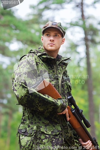 Image of young soldier or hunter with gun in forest