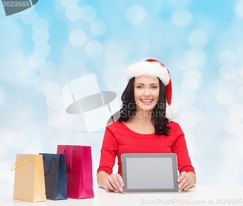 Image of smiling woman with shopping bags and tablet pc