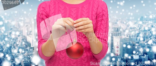 Image of close up of woman in sweater with christmas ball