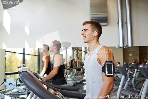 Image of man with smartphone exercising on treadmill in gym