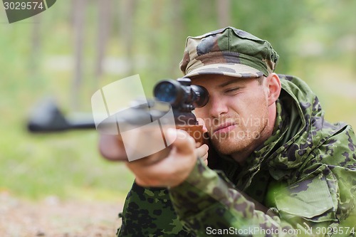 Image of young soldier or hunter with gun in forest