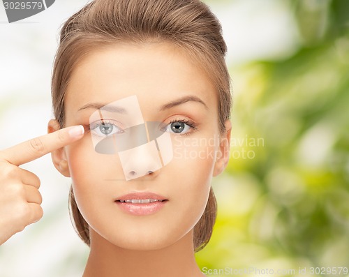 Image of beautiful young woman pointing finger to her eye