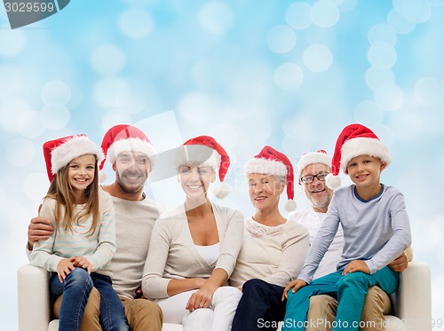 Image of happy family in santa helper hats sitting on couch