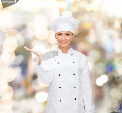Image of smiling female chef holding something on hand