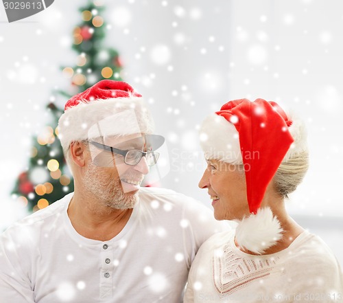 Image of happy senior couple in santa helper hats at home